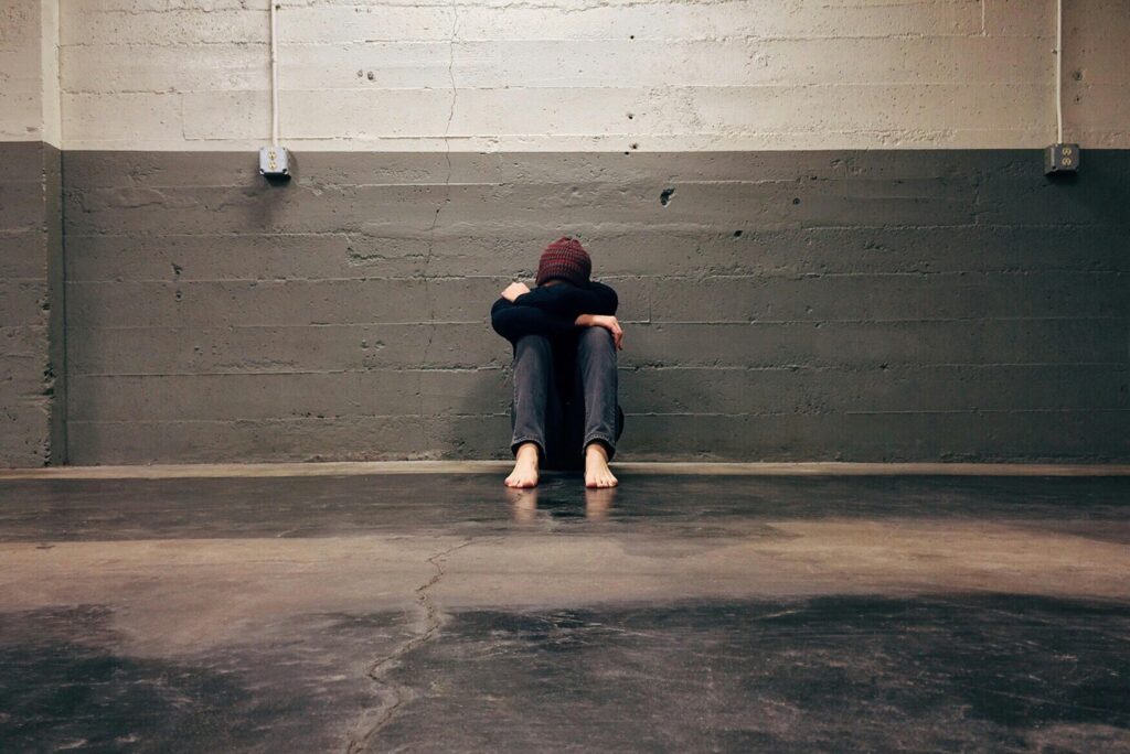 Person leaning on a grey and white brick wall with head in hands