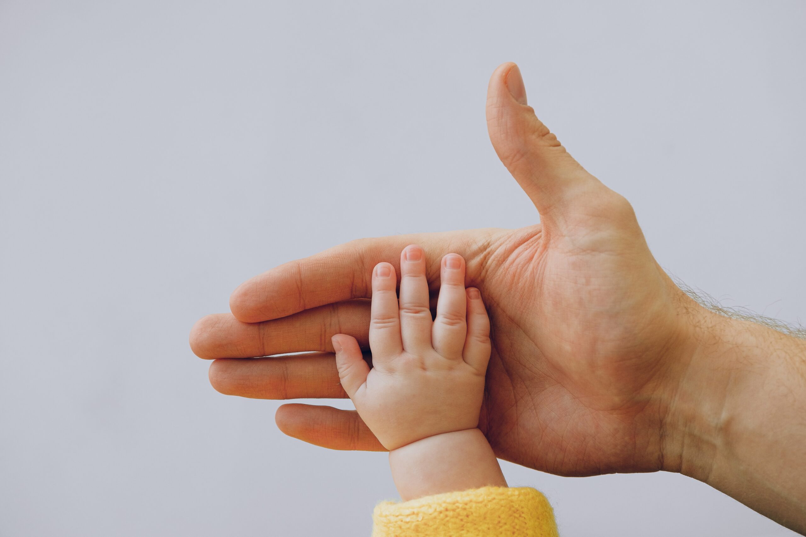 A baby's hand against a Father's Hand