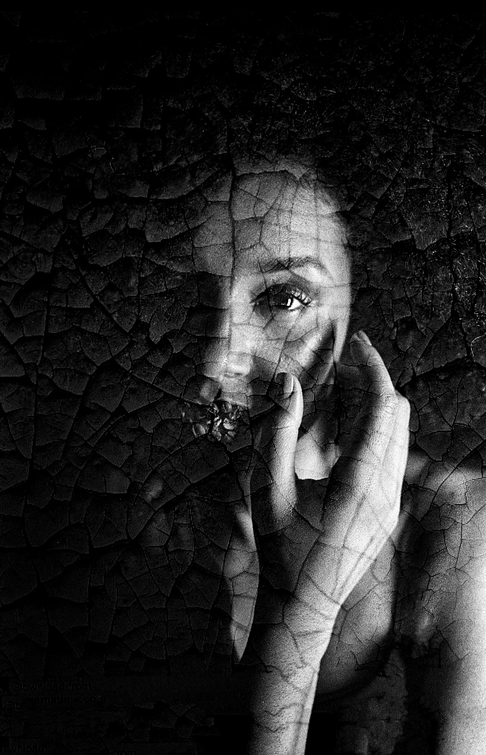 Gentle mysterious woman touching face in darkness cracked/burnt look