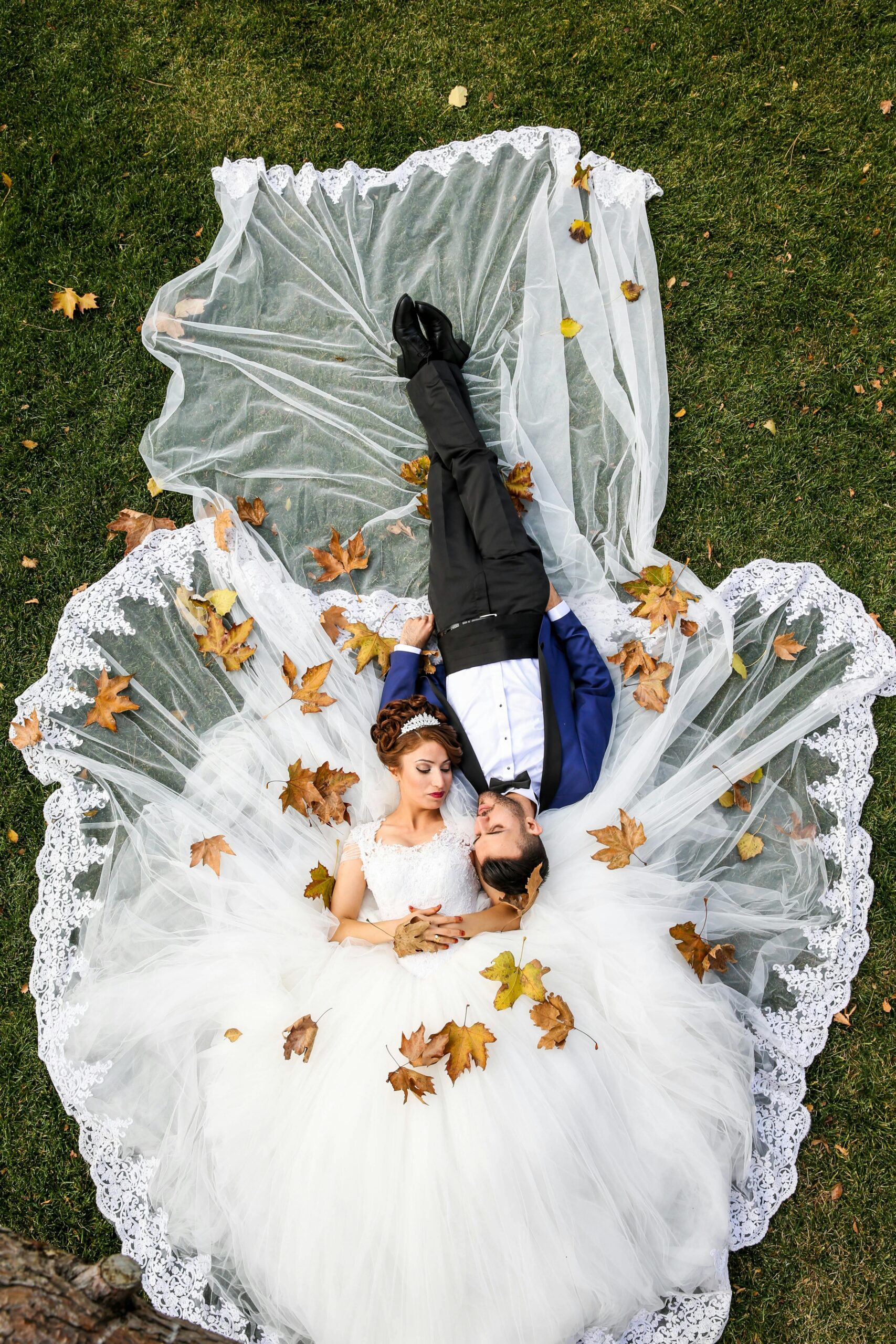 Aerial Photo of a bride and groom lying on Grass Field with autumn leaves